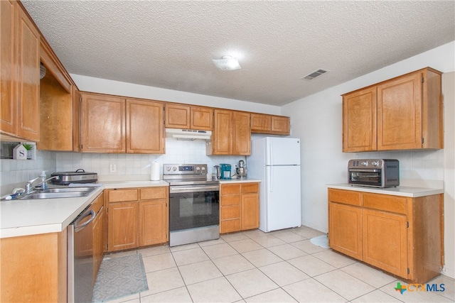 kitchen with stainless steel appliances, light tile patterned flooring, sink, tasteful backsplash, and a textured ceiling