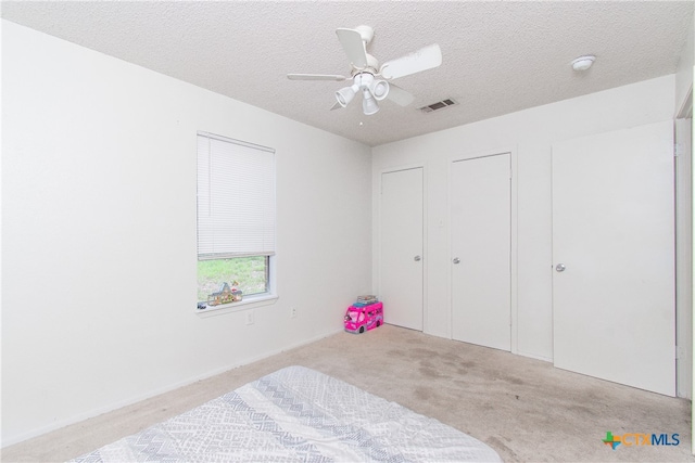 bedroom featuring ceiling fan, a textured ceiling, and light colored carpet