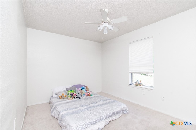 bedroom featuring a textured ceiling, light carpet, and ceiling fan