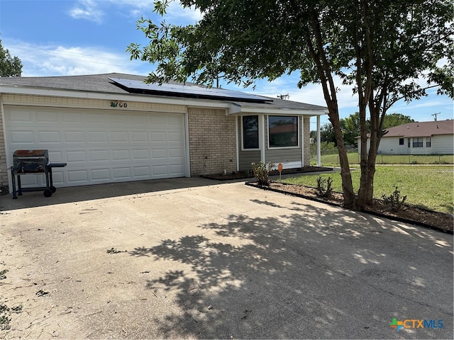 single story home with a front lawn, a garage, and solar panels