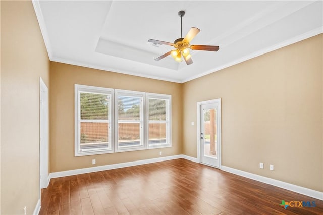 empty room featuring baseboards, a ceiling fan, crown molding, a raised ceiling, and wood-type flooring
