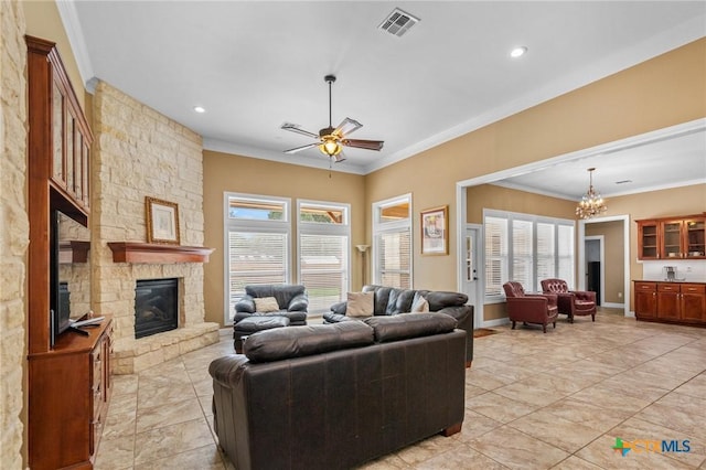 living room with a fireplace, ornamental molding, visible vents, and ceiling fan with notable chandelier