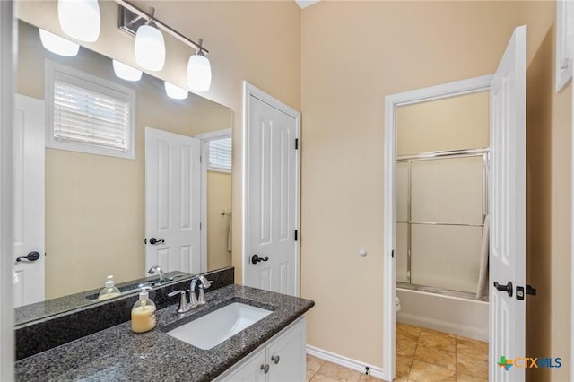 bathroom with tile patterned flooring, combined bath / shower with glass door, vanity, and a wealth of natural light