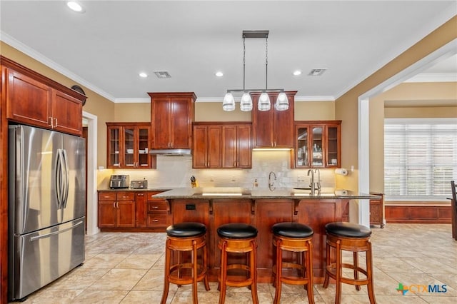kitchen featuring a kitchen bar, glass insert cabinets, a sink, and freestanding refrigerator