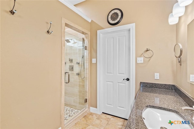 bathroom featuring a shower stall, a sink, baseboards, ornamental molding, and tile patterned flooring