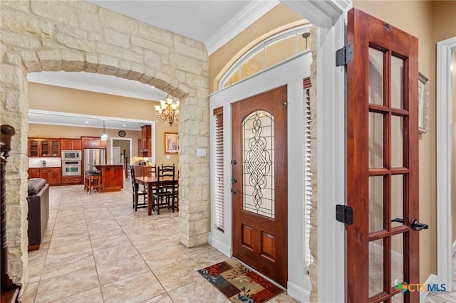 entryway with a notable chandelier and ornamental molding