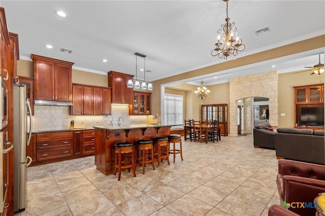 kitchen with a kitchen breakfast bar, crown molding, open floor plan, visible vents, and freestanding refrigerator