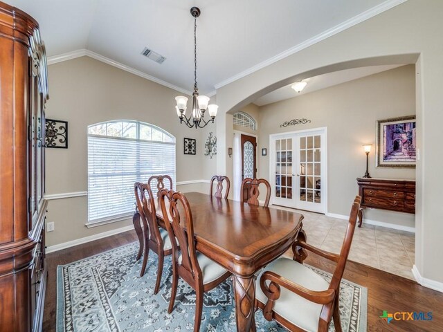 dining area featuring french doors, visible vents, wood finished floors, arched walkways, and vaulted ceiling