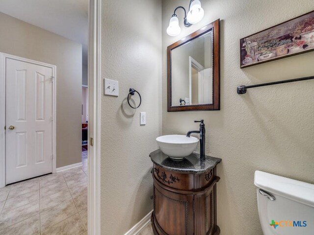 half bathroom featuring baseboards, toilet, tile patterned floors, and vanity