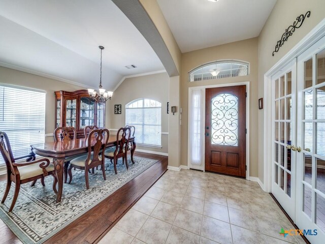 entryway with lofted ceiling, light tile patterned floors, visible vents, arched walkways, and an inviting chandelier