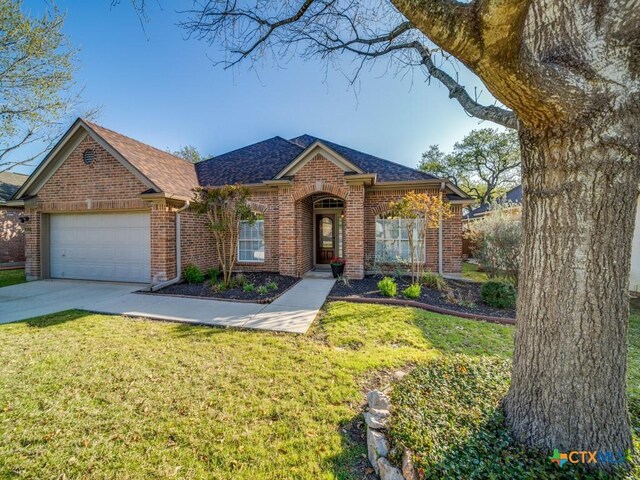 view of front of house featuring driveway, brick siding, a garage, and a front yard