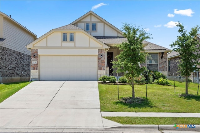 532 Elm Green St, Hutto, TX 78634 - tudor-style house featuring concrete driveway, a front yard, an attached garage, a shingled roof, and stone siding