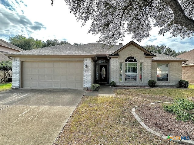 203 Canyon Crk, Victoria, TX 77901 - view of front facade with brick siding, concrete driveway, a garage, and a front yard