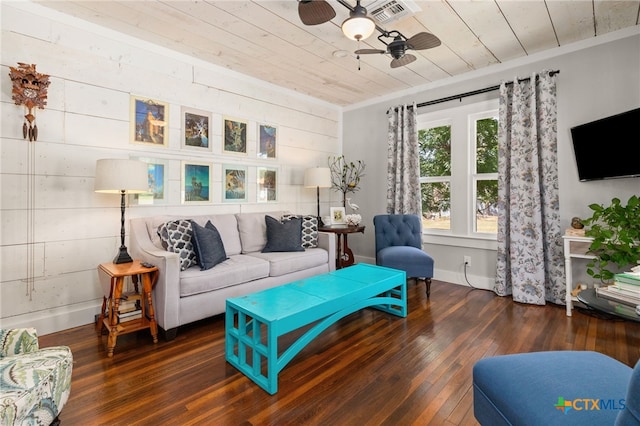 living room with dark wood-type flooring, wood ceiling, wood walls, ornamental molding, and ceiling fan