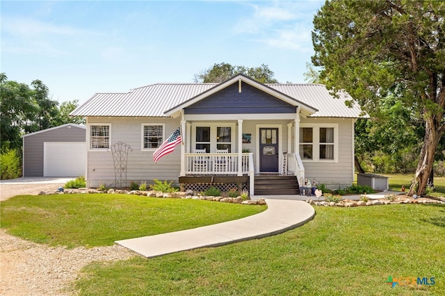 view of front of property with an outbuilding, covered porch, a garage, and a front yard