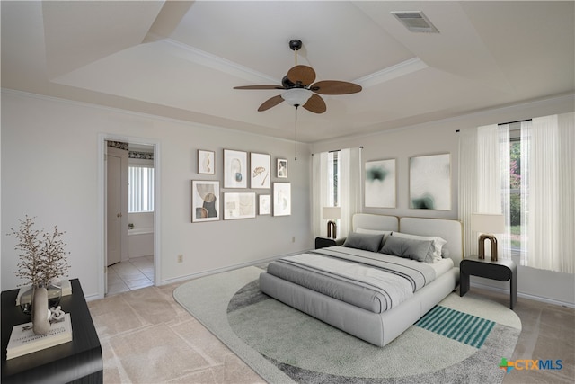 bedroom with crown molding, connected bathroom, a raised ceiling, light colored carpet, and ceiling fan