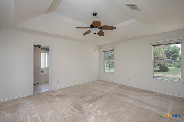 carpeted empty room featuring plenty of natural light, ceiling fan, crown molding, and a tray ceiling