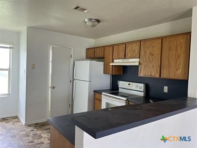 1200 Industrial Blvd, Killeen, TX 76549 - kitchen featuring dark countertops, visible vents, white appliances, and brown cabinetry