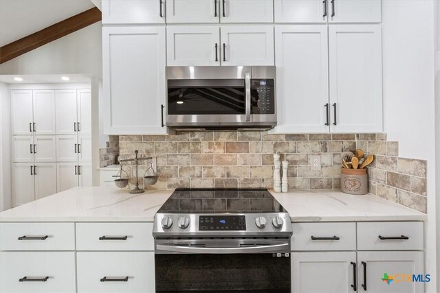 kitchen with white cabinets, stainless steel appliances, light stone counters, and decorative backsplash