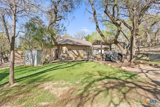 view of yard with a pergola, a shed, and an outbuilding