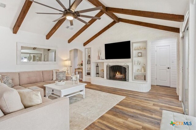 living room with a ceiling fan, arched walkways, wood finished floors, and visible vents