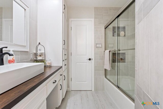 bathroom with vanity and bath / shower combo with glass door