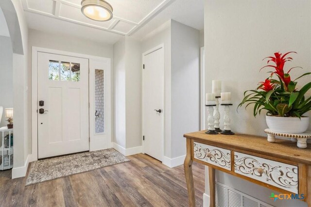 foyer entrance with baseboards, wood finished floors, and arched walkways