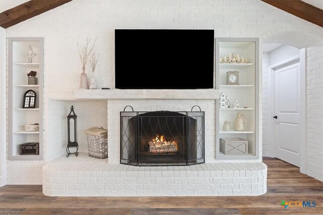 room details featuring a fireplace, wood finished floors, and built in shelves