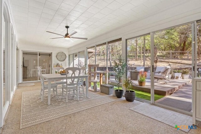 unfurnished sunroom with a ceiling fan and outdoor dining area