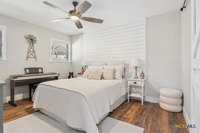 bedroom featuring baseboards, ceiling fan, and dark wood-type flooring