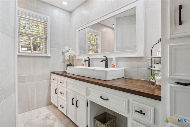 bathroom featuring vanity, tile walls, and decorative backsplash