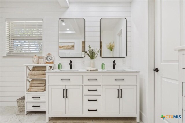 bathroom with double vanity, a sink, and wooden walls