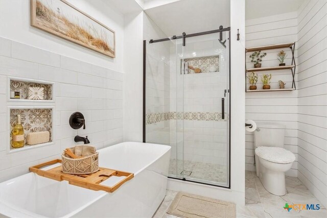 full bathroom with tile walls, toilet, a soaking tub, marble finish floor, and a stall shower