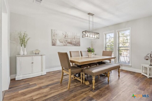 dining area with baseboards, visible vents, and wood finished floors