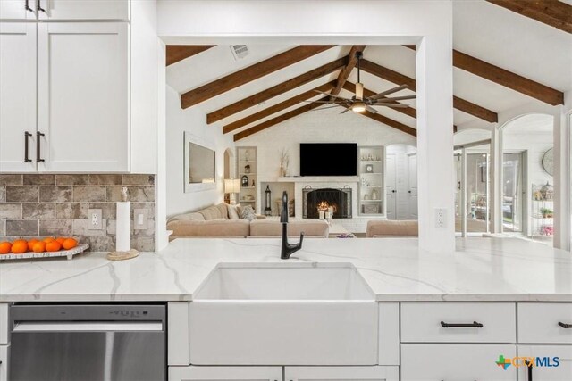 kitchen featuring white cabinetry, stainless steel dishwasher, a sink, light stone counters, and ceiling fan