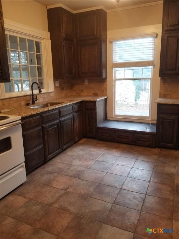 kitchen featuring tasteful backsplash, crown molding, light stone countertops, white range with electric cooktop, and a sink