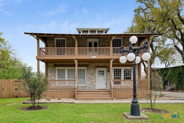 view of front of home with a front yard, a balcony, fence, and covered porch