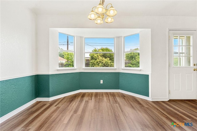 809 Filly Ln, Temple, TX 76504 - unfurnished dining area featuring wood finished floors, healthy amount of natural light, a chandelier, baseboards, and a textured wall