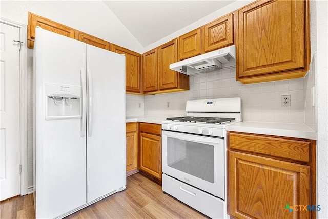 809 Filly Ln, Temple, TX 76504 - kitchen with white appliances, under cabinet range hood, lofted ceiling, light wood-style flooring, and light countertops