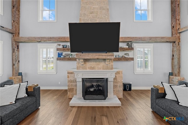 8300 Spicewood Springs Rd, China Spring, TX 76633 - living area featuring a fireplace with raised hearth, wood finished floors, plenty of natural light, baseboards, and a towering ceiling