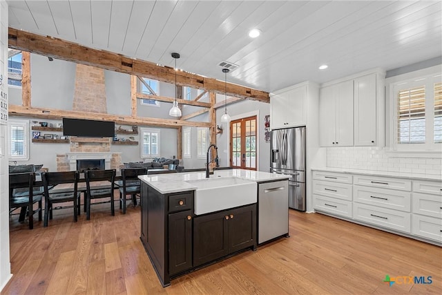 8300 Spicewood Springs Rd, China Spring, TX 76633 - kitchen with a sink, stainless steel appliances, white cabinetry, beam ceiling, and light wood-style floors
