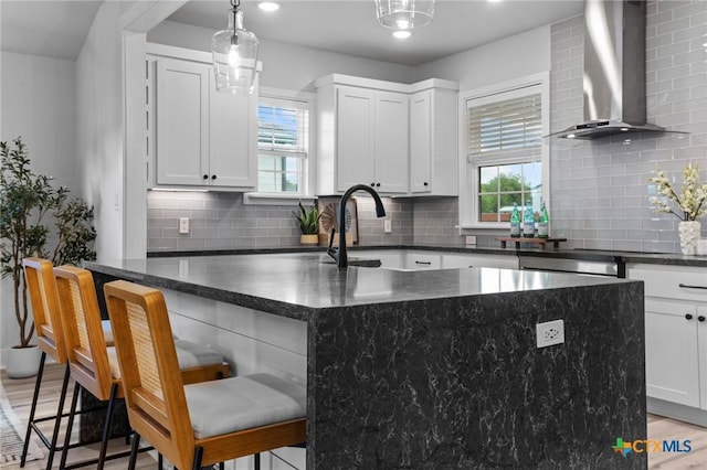 4430 Cedar Creek Rd, Temple, TX 76504 - kitchen featuring wall chimney range hood, healthy amount of natural light, tasteful backsplash, light wood-type flooring, and recessed lighting