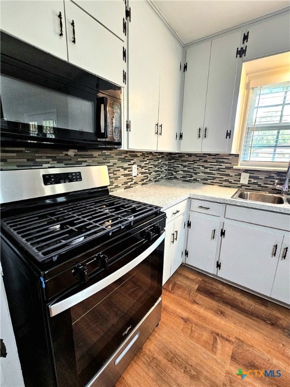 kitchen with stainless steel range with gas cooktop, white cabinets, light wood-type flooring, and tasteful backsplash