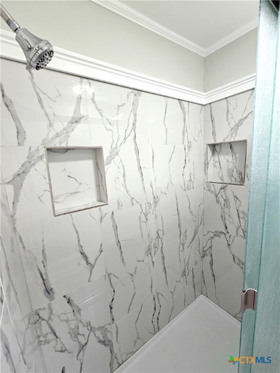 bathroom with ornamental molding and a tile shower