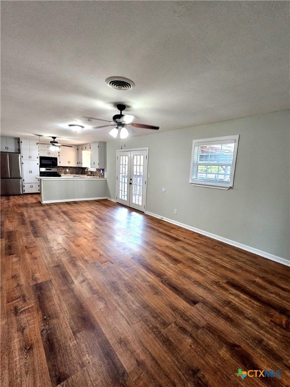 unfurnished living room featuring dark hardwood / wood-style flooring, french doors, and a healthy amount of sunlight