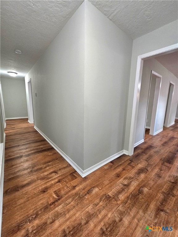 corridor featuring a textured ceiling and dark hardwood / wood-style floors