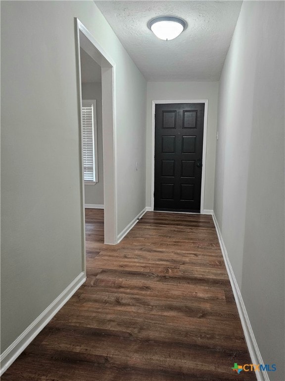 doorway to outside with dark wood-type flooring and a textured ceiling