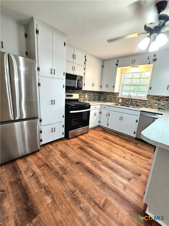 kitchen featuring backsplash, appliances with stainless steel finishes, sink, and hardwood / wood-style flooring