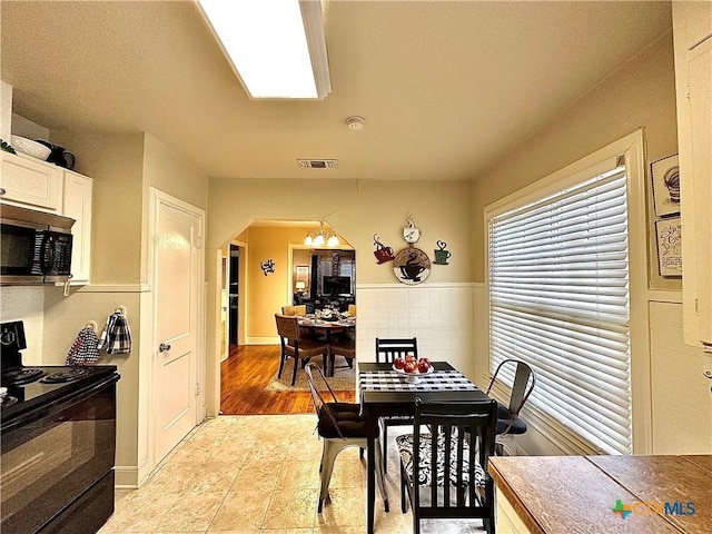 dining room with arched walkways, visible vents, and a notable chandelier