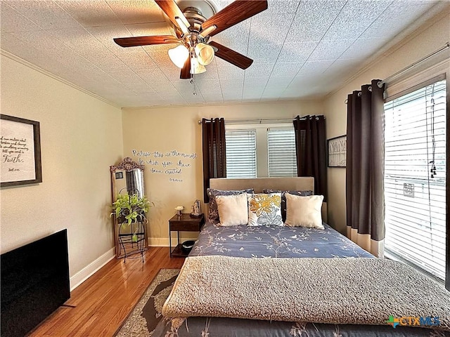 bedroom featuring ceiling fan, wood finished floors, and baseboards